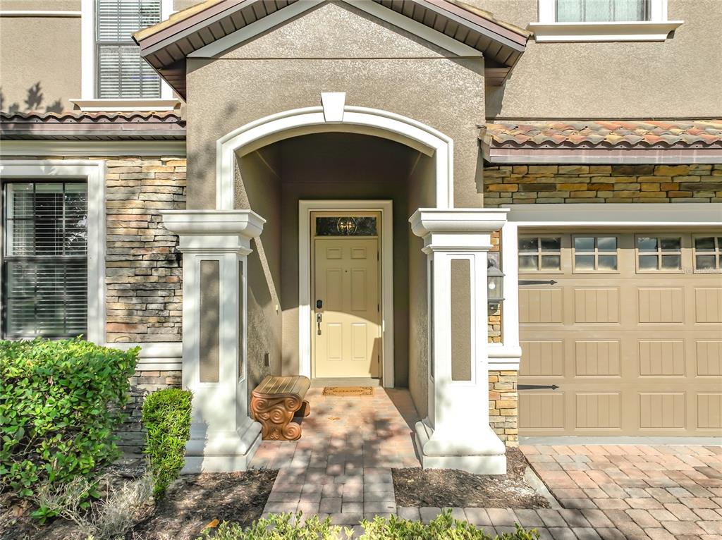 The exterior of a house features a stone facade, a beige door, and a garage — 1505 ROLLING FAIRWAY DRIVE, DAVENPORT, FL