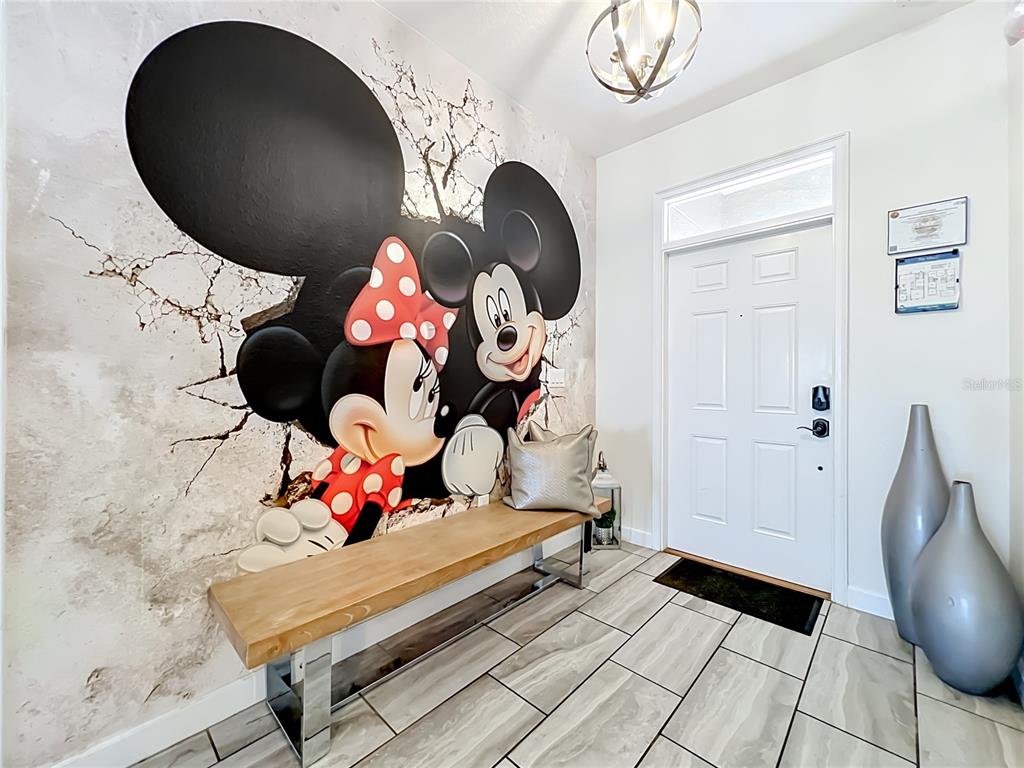 An entryway features a Mickey and Minnie Mouse wall mural, a wooden bench, and tile flooring — 1505 ROLLING FAIRWAY DRIVE, DAVENPORT, FL