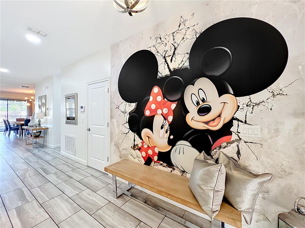 A hallway features a large Mickey and Minnie Mouse wall mural above a wooden bench — 1505 ROLLING FAIRWAY DRIVE, DAVENPORT, FL