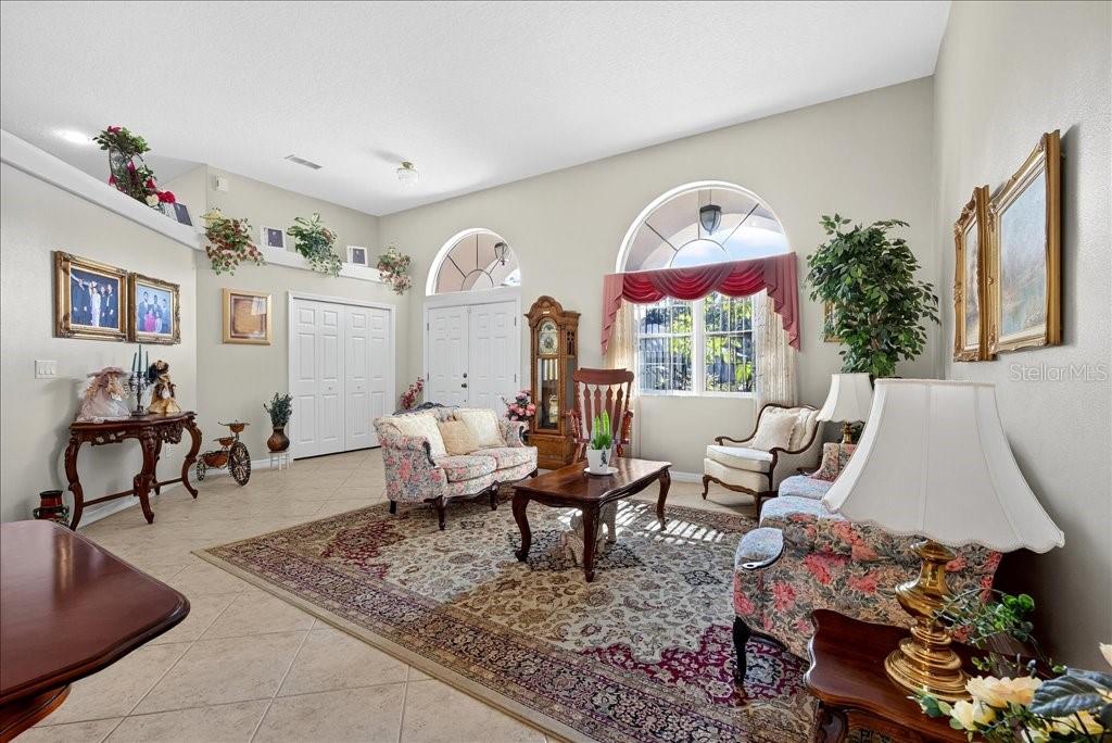 A formal living room features a large area rug, floral furniture, and arched windows — 28 FANSHAWE LANE, PALM COAST, FL