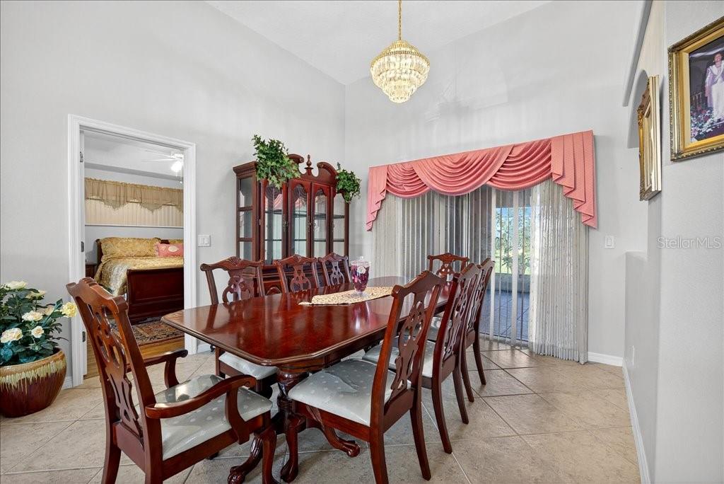 A dining room features a wooden table, six chairs, a china cabinet, and pink valances — 28 FANSHAWE LANE, PALM COAST, FL