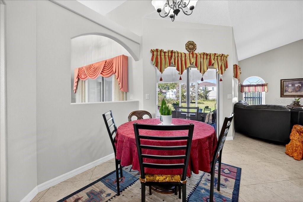 A dining area features a round table with a red cloth, tile floors, and sliding doors — 28 FANSHAWE LANE, PALM COAST, FL