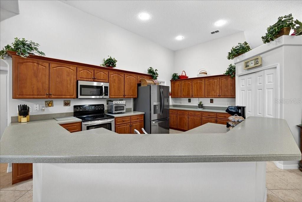 A kitchen features wood cabinets, gray countertops, stainless steel appliances, and a breakfast bar — 28 FANSHAWE LANE, PALM COAST, FL