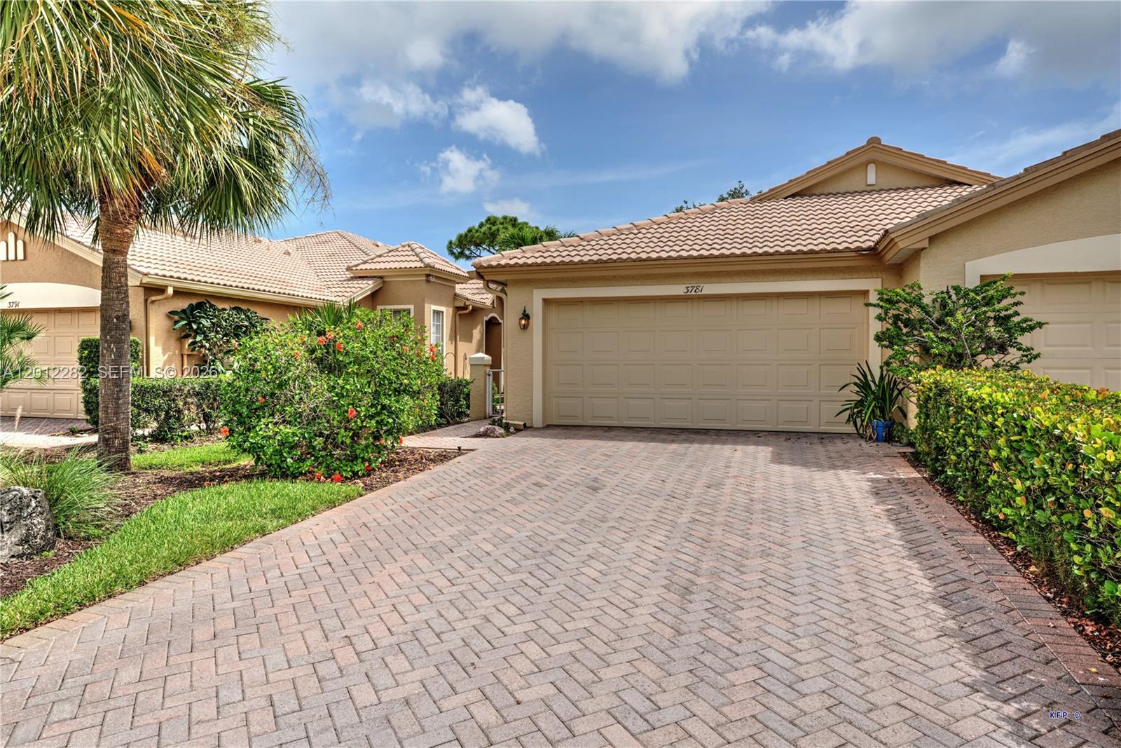 A beige house with a tiled roof and a brick driveway features a two-car garage — 3781 NW Willow Creek Dr, Jensen Beach FL 34957, JENSEN BEACH, FL