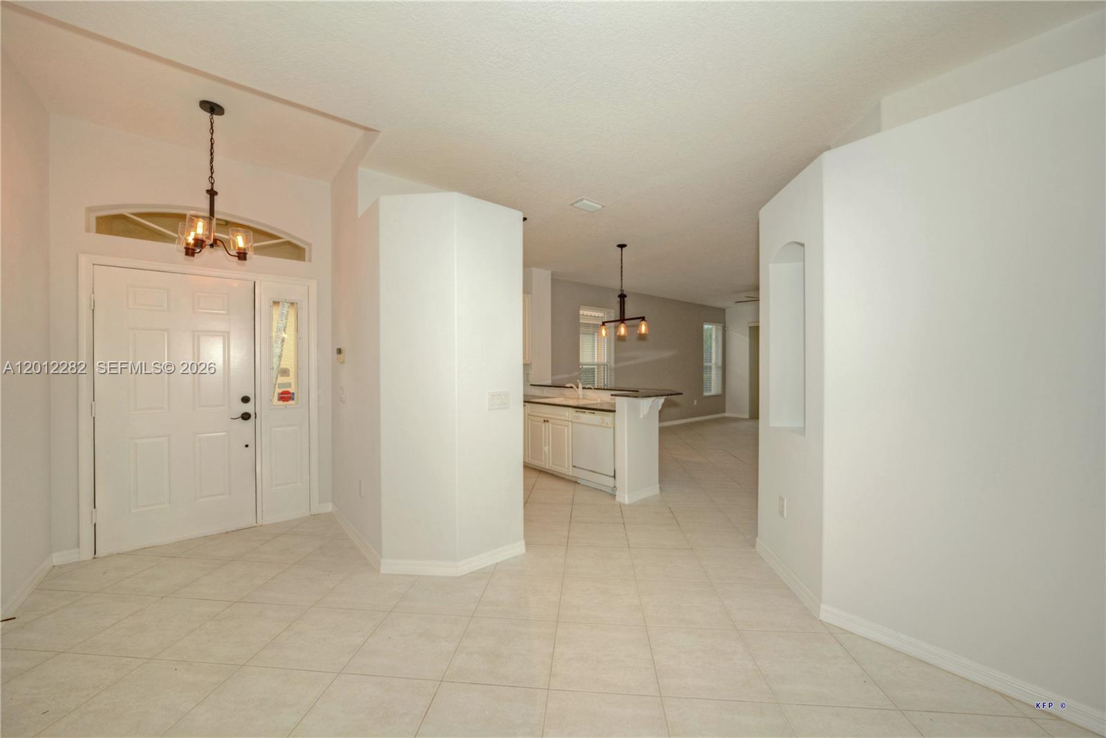 An entryway with tile flooring leads to a kitchen featuring a breakfast bar and lighting — 3781 NW Willow Creek Dr, Jensen Beach FL 34957, JENSEN BEACH, FL