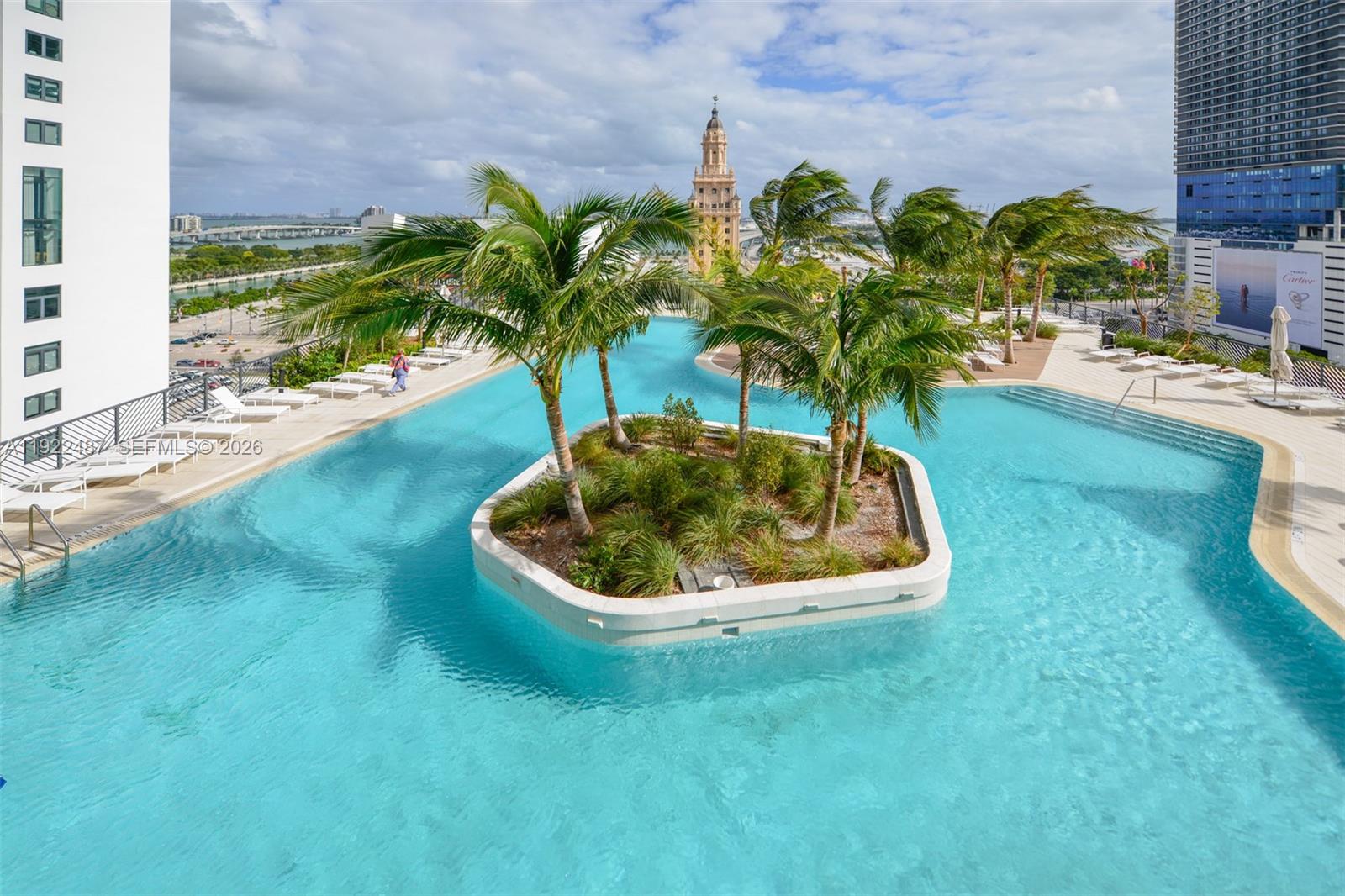 An elevated outdoor swimming pool features a central island with palm trees and landscaping — 159 NE 6th St # 4601, Miami FL 33132, MIAMI, FL