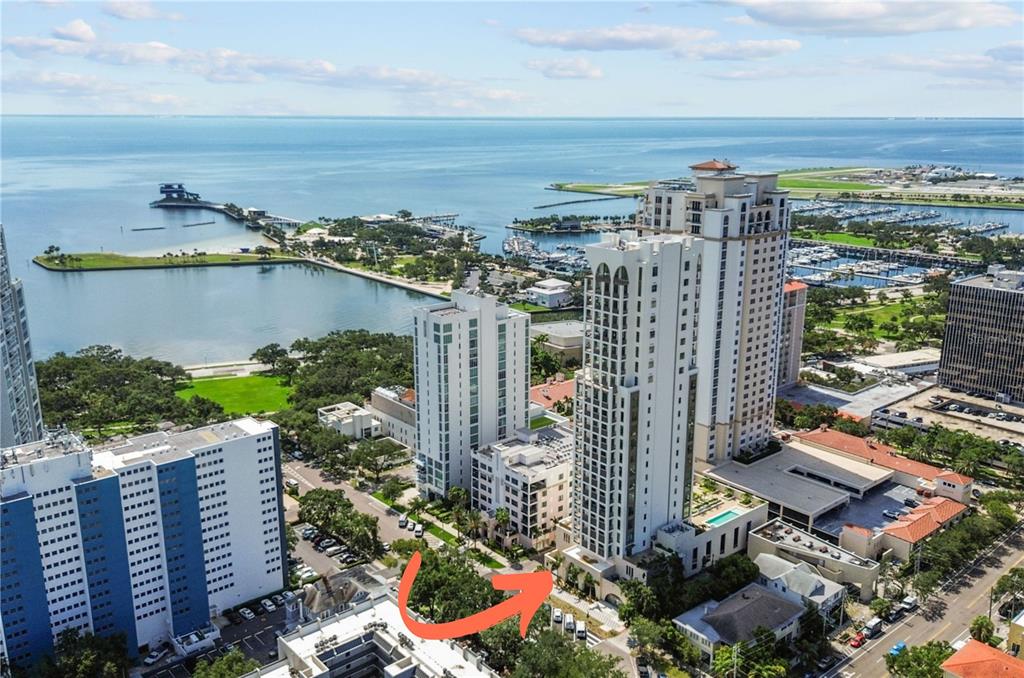An aerial view shows a tall residential building near a bay with a marina nearby — 126 4TH AVENUE NE UNIT 601, ST PETERSBURG, FL