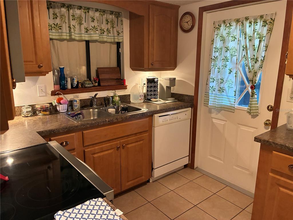 A kitchen features wood cabinets, a double sink, a white dishwasher, and a glass door — 10310 SW 91ST COURT, OCALA, FL