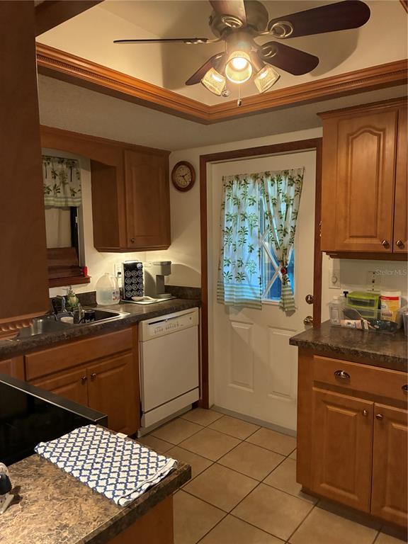 A kitchen features wood cabinets, a white dishwasher, a ceiling fan, and tiled flooring — 10310 SW 91ST COURT, OCALA, FL