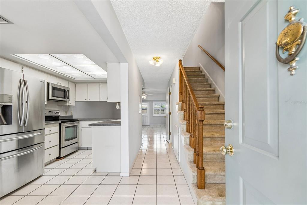 A view from an entryway showing a kitchen, a staircase, and a tiled hallway — 2131 RIDGE ROAD S UNIT 99, LARGO, FL
