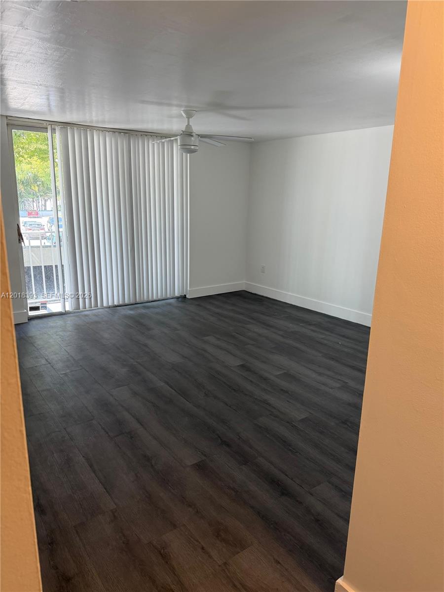 An empty room features dark wood-look flooring, white walls, a ceiling fan, and sliding doors — 1740 NW N River Dr # 325, Miami FL 33125, MIAMI, FL