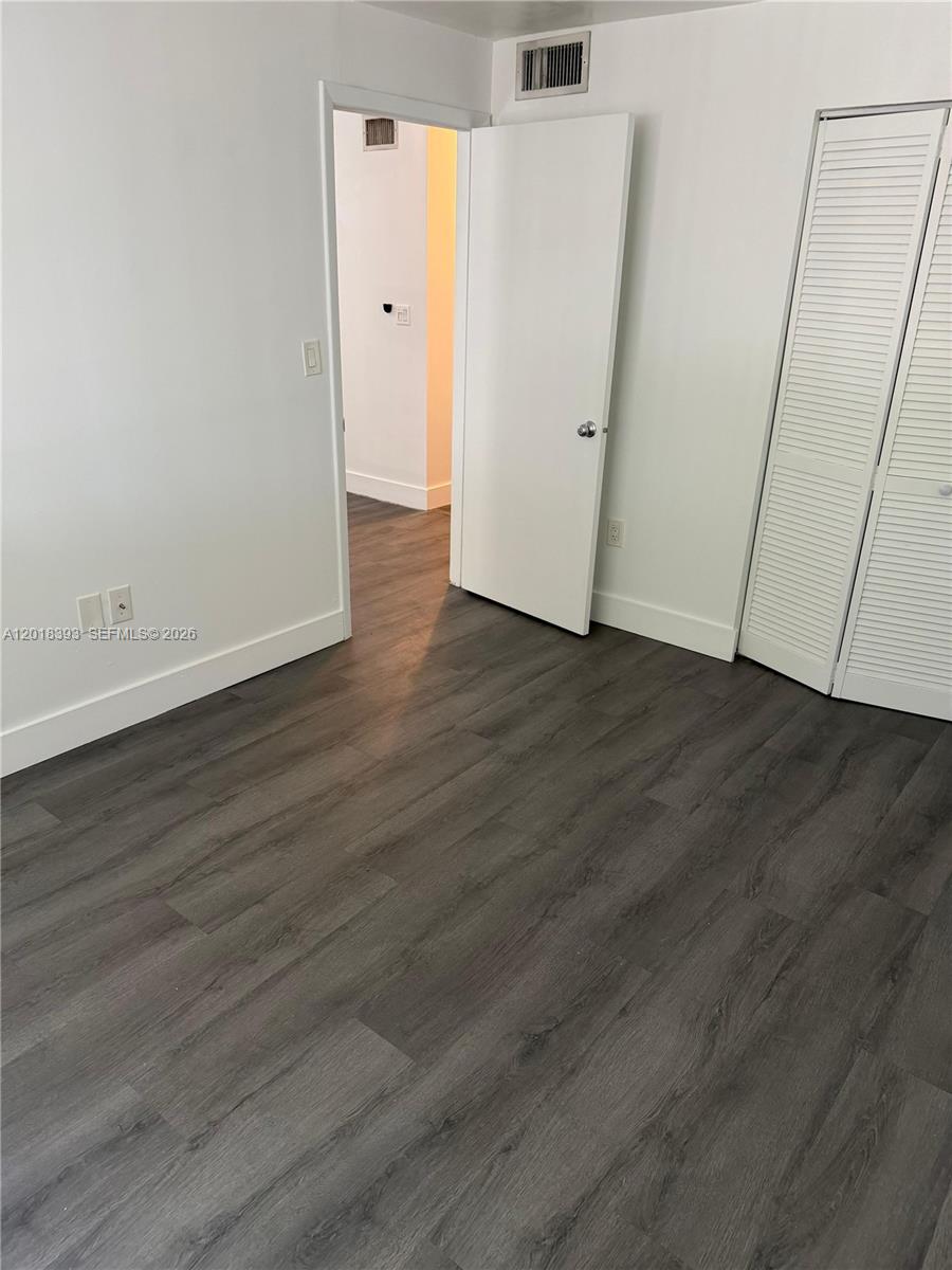 This room features white walls, dark wood-look flooring, a closet with louvered doors, and a doorway — 1740 NW N River Dr # 325, Miami FL 33125, MIAMI, FL