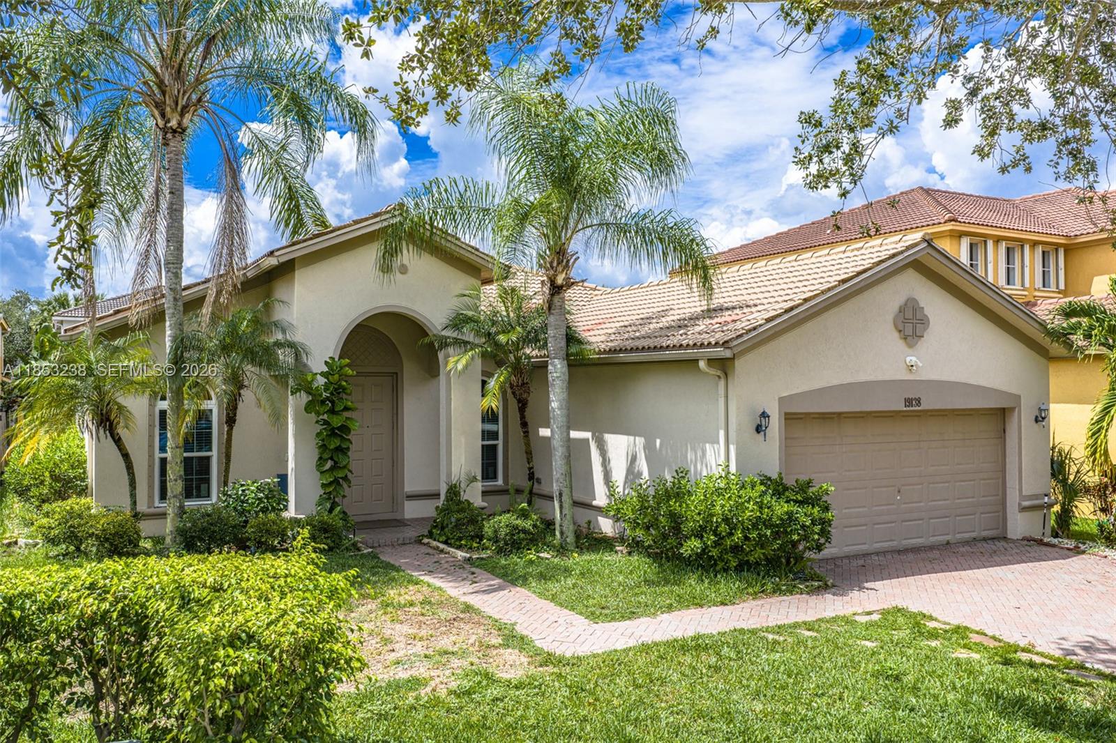 A single-story house with a beige stucco exterior, a tiled roof, and a two-car garage — 19138 Stonebrook St, Weston FL 33332, WESTON, FL