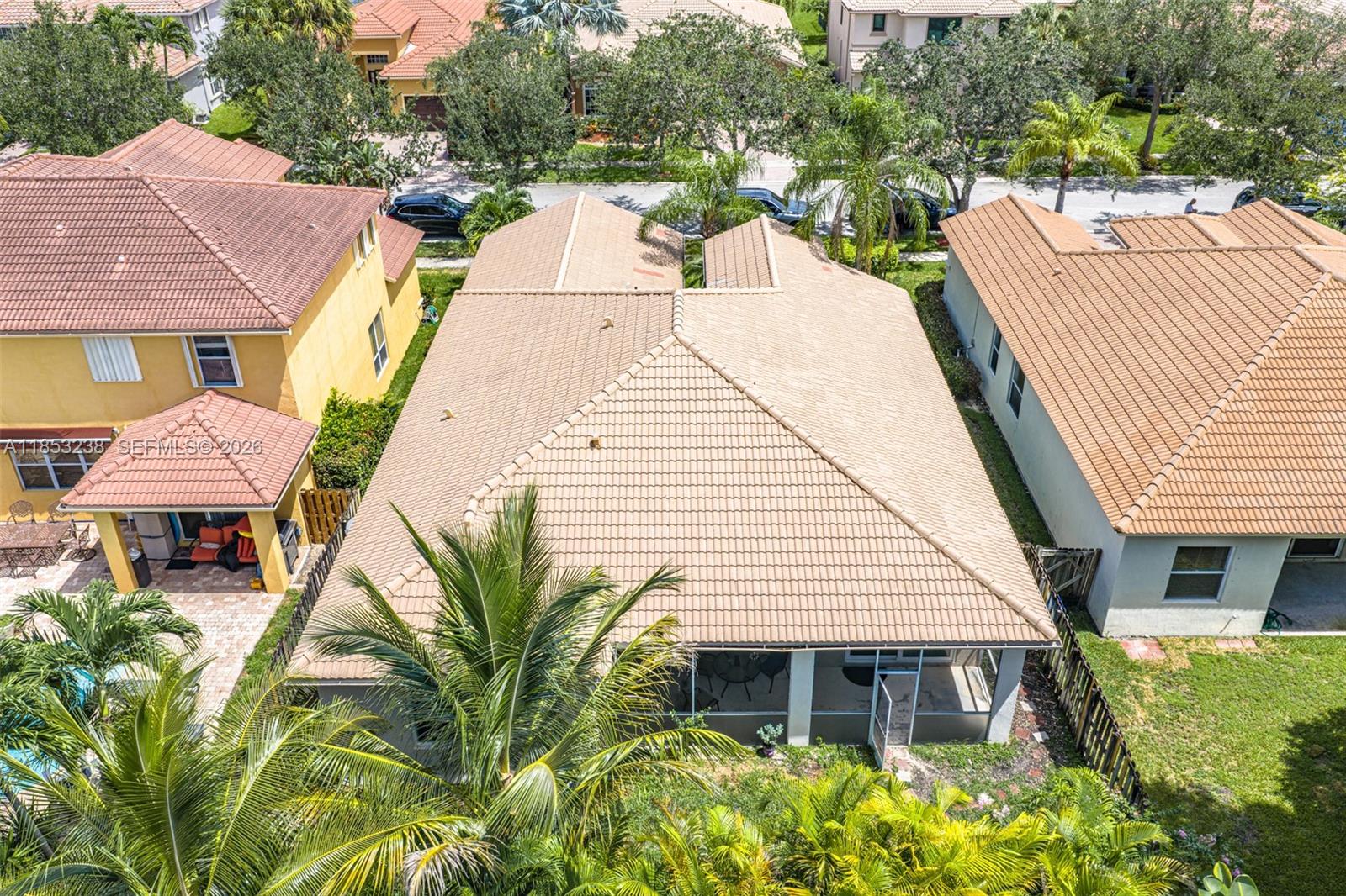 An aerial view shows the tiled roofs of three suburban houses and surrounding palm trees — 19138 Stonebrook St, Weston FL 33332, WESTON, FL