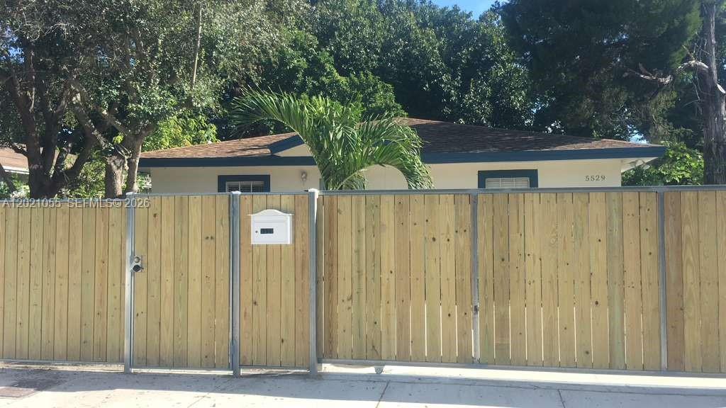 A single-story house is partially obscured by a tall wooden privacy fence and a palm tree — 5529 NW 4th Ave # 2, Miami FL 33127, MIAMI, FL