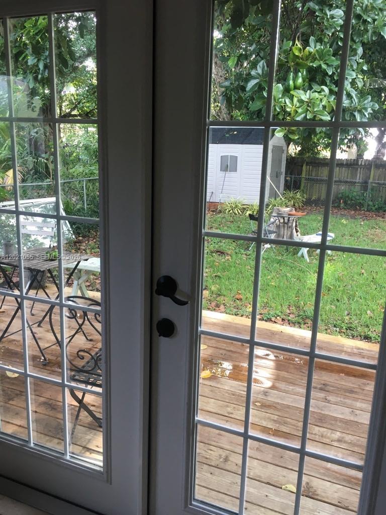 A view through glass French doors looking out onto a wooden deck and backyard — 5529 NW 4th Ave # 2, Miami FL 33127, MIAMI, FL