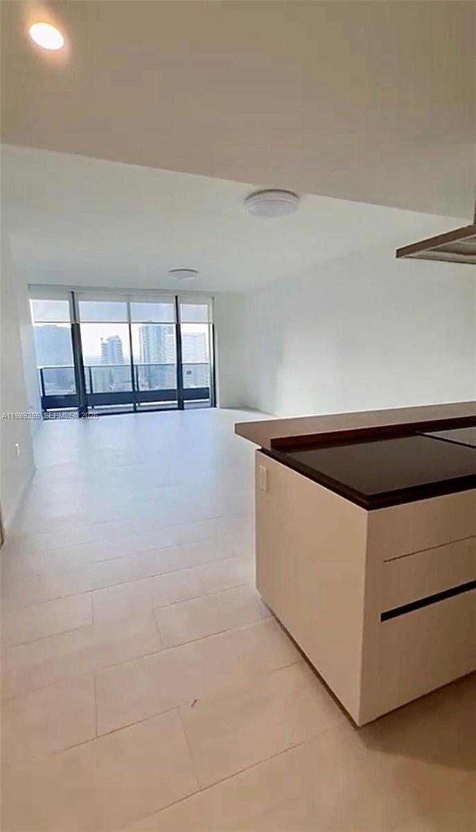 An open-concept living area features light tile flooring, white walls, and a kitchen island — 1000 brickell plz # 2008, Miami FL 33131, MIAMI, FL