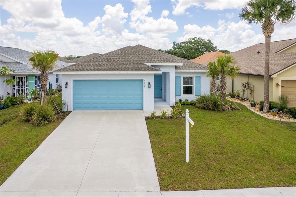 A single-story house with a blue garage door, light blue shutters, and a concrete driveway — 573 ROSE APPLE CIRCLE, PORT CHARLOTTE, FL