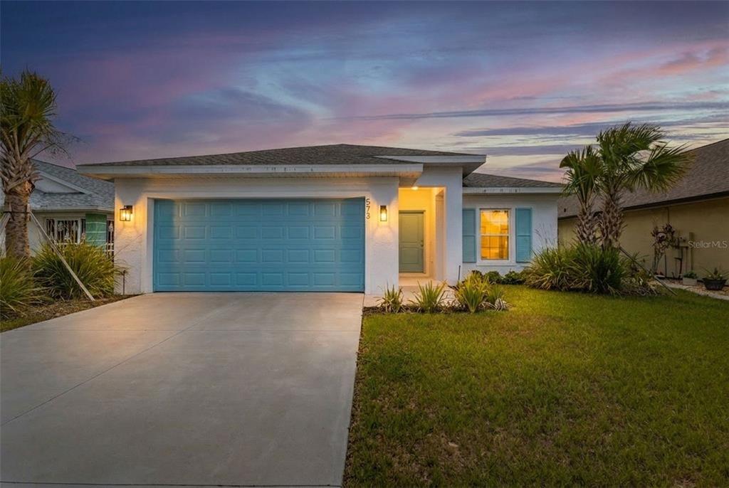 A single-story house with a blue garage door, white stucco walls, and a concrete driveway — 573 ROSE APPLE CIRCLE, PORT CHARLOTTE, FL