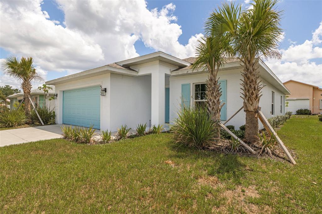 A white single-story house with a light blue garage door and two palm trees — 573 ROSE APPLE CIRCLE, PORT CHARLOTTE, FL