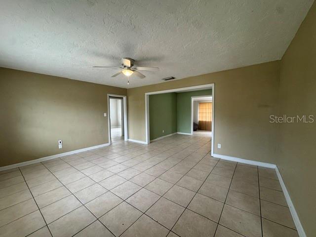 An interior view of a room with beige walls, tile flooring, and a ceiling fan — 2976 POPLAR STREET, SARASOTA, FL