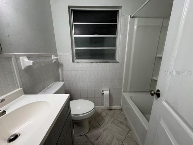 A bathroom features a white vanity, a toilet, and a shower-tub combination with tiled walls — 2976 POPLAR STREET, SARASOTA, FL