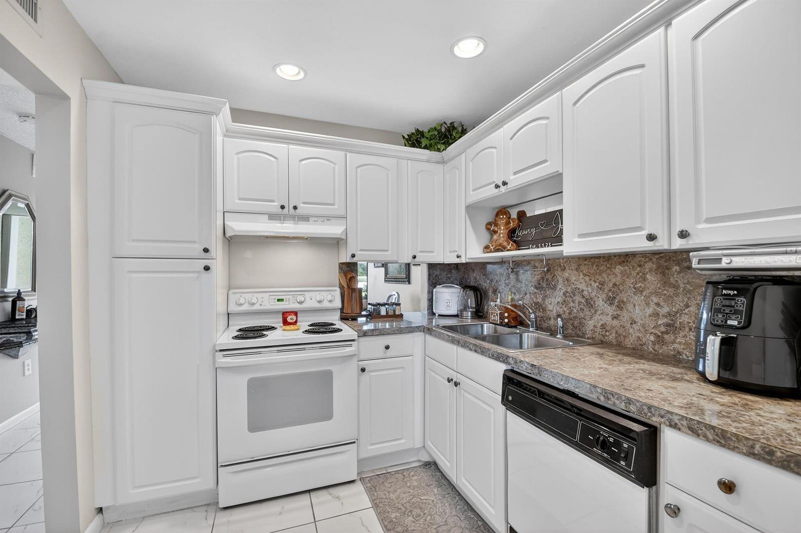 A kitchen features white cabinets, a white stove, a double sink, and brown countertops — 4272 Deste Court # 106, Lake Worth FL 33467, LAKE WORTH, FL