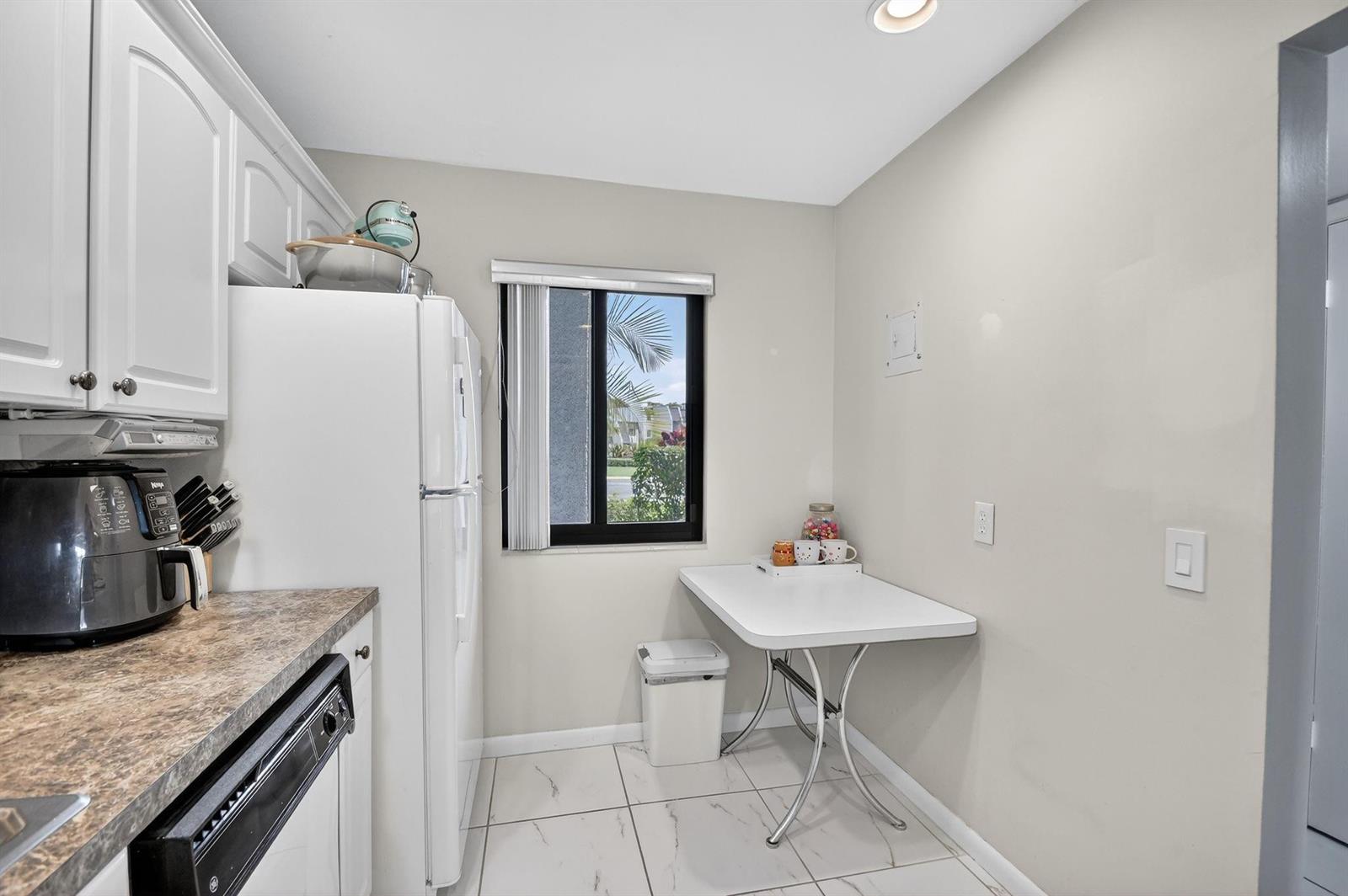 A kitchen features white cabinets, a white refrigerator, a small dining table, and tiled floors — 4272 Deste Court # 106, Lake Worth FL 33467, LAKE WORTH, FL