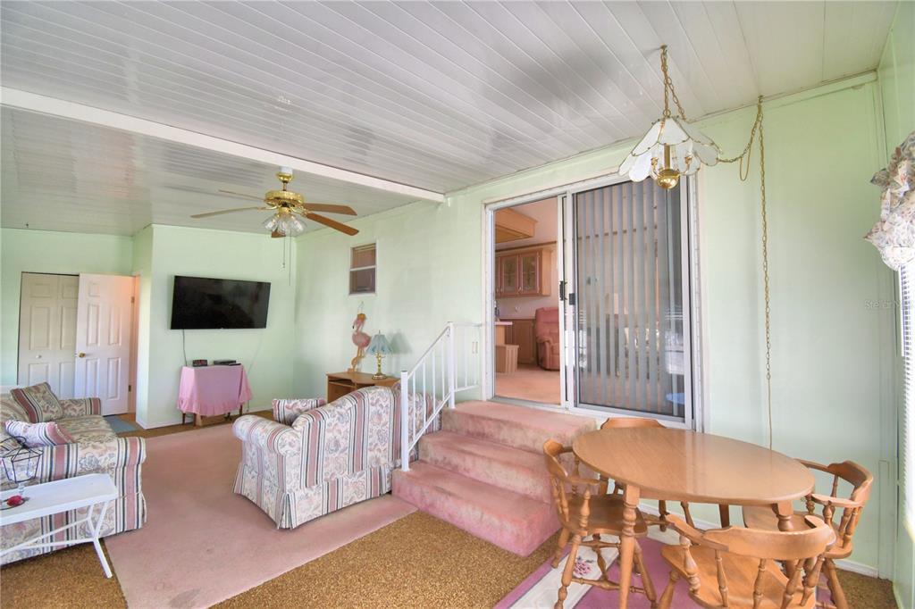 A sunroom features a dining set, a living area with two sofas, and pink carpeting — 251 PATTERSON ROAD UNIT H54, HAINES CITY, FL