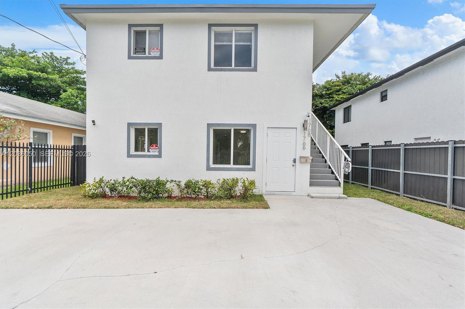 A two-story white building with a concrete driveway and an exterior staircase — 1766 NW 68th Ter, Miami FL 33147, MIAMI, FL