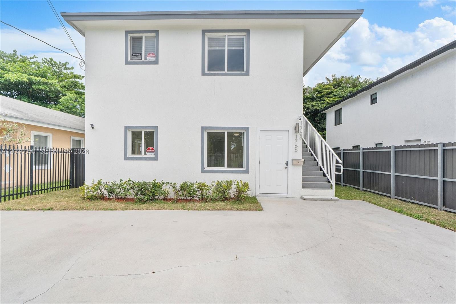 A two-story white building with an exterior staircase and a concrete driveway in front — 1766 NW 68th Ter, Miami FL 33147, MIAMI, FL
