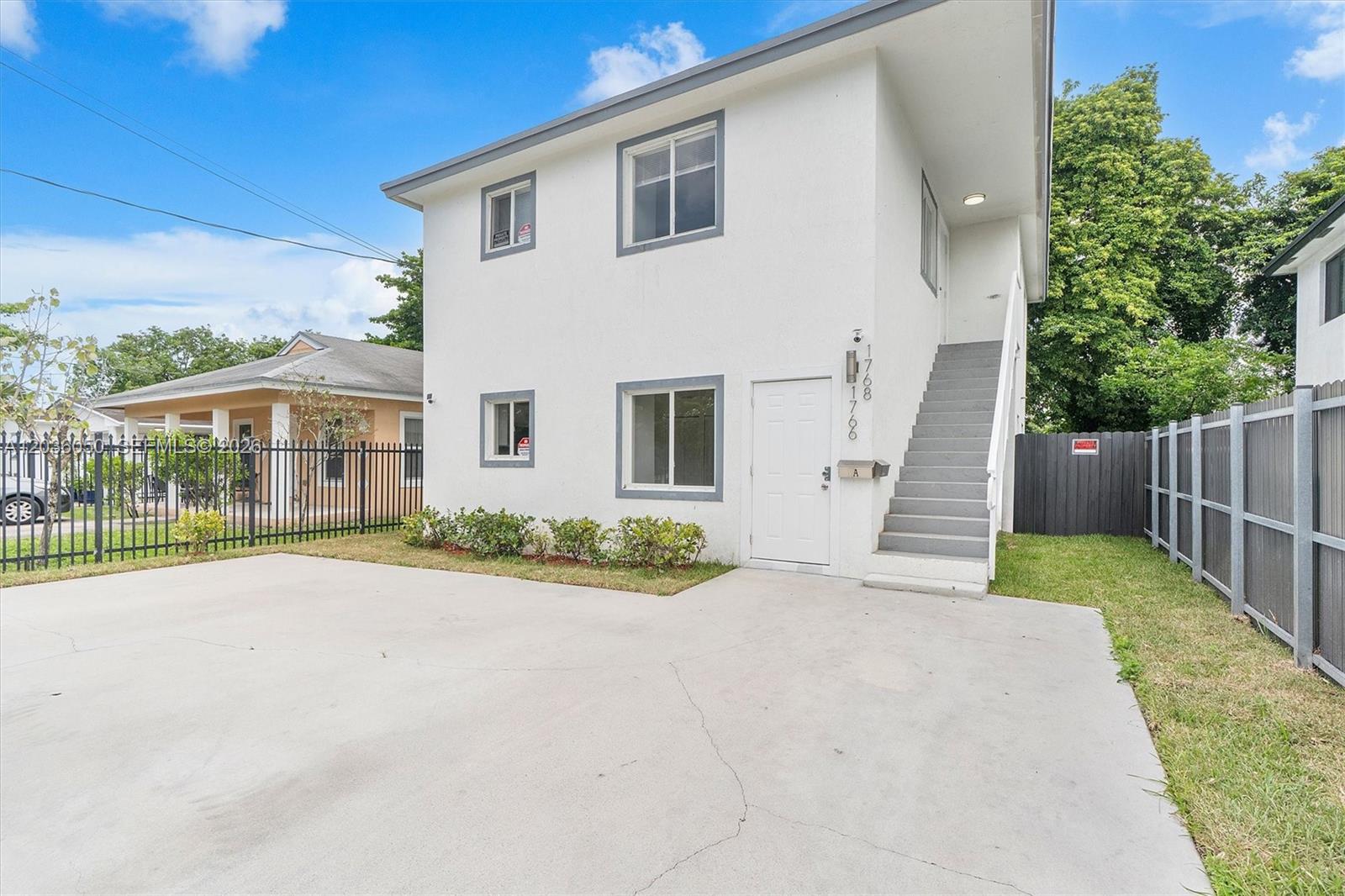 A two-story white stucco building features an external staircase and a concrete driveway — 1766 NW 68th Ter, Miami FL 33147, MIAMI, FL