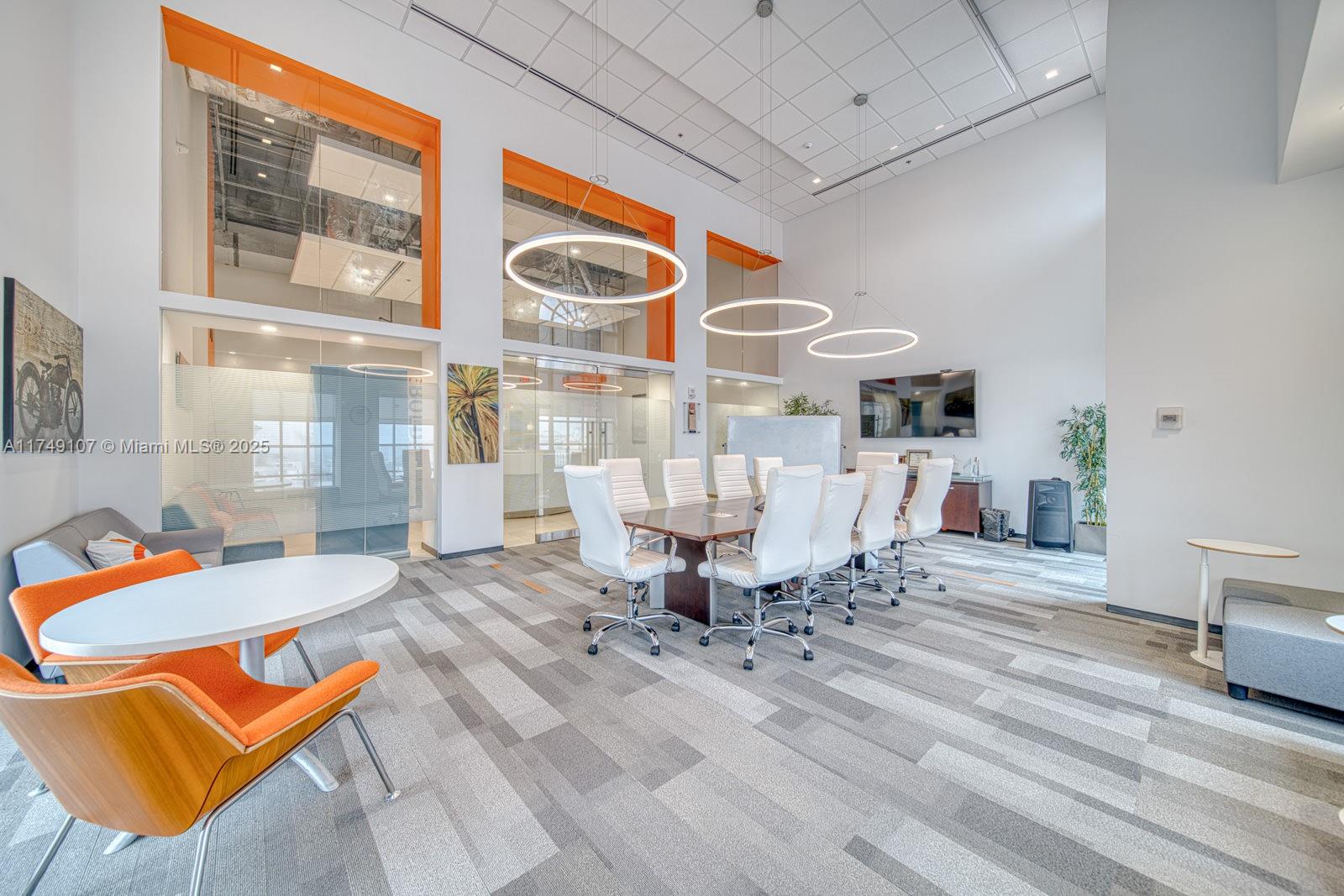 A modern office conference room features a large table, white chairs, and orange accent walls — 2 Alhambra Plz # A, Coral Gables FL 33134, CORAL GABLES, FL