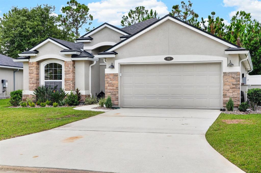 A single-story house with a beige stucco exterior, stone accents, and a two-car garage — 86 LITTLE OWL LANE, ST AUGUSTINE, FL