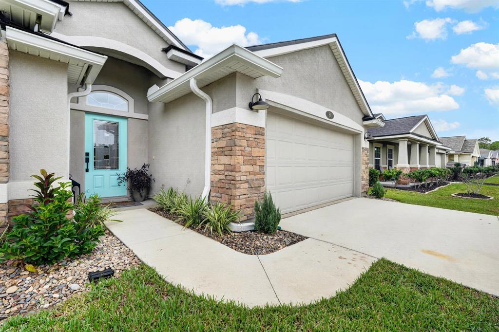 The exterior of a single-story house features a light blue front door and stone accents — 86 LITTLE OWL LANE, ST AUGUSTINE, FL