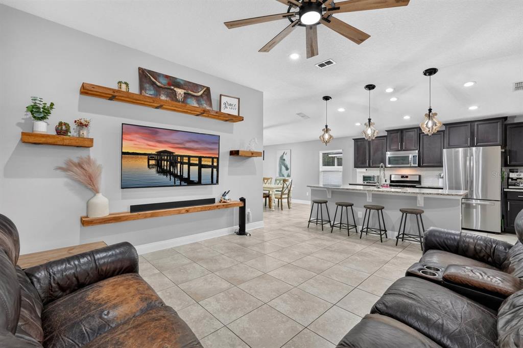 An open-concept living room and kitchen featuring tile floors, wood shelving, and a ceiling fan — 86 LITTLE OWL LANE, ST AUGUSTINE, FL