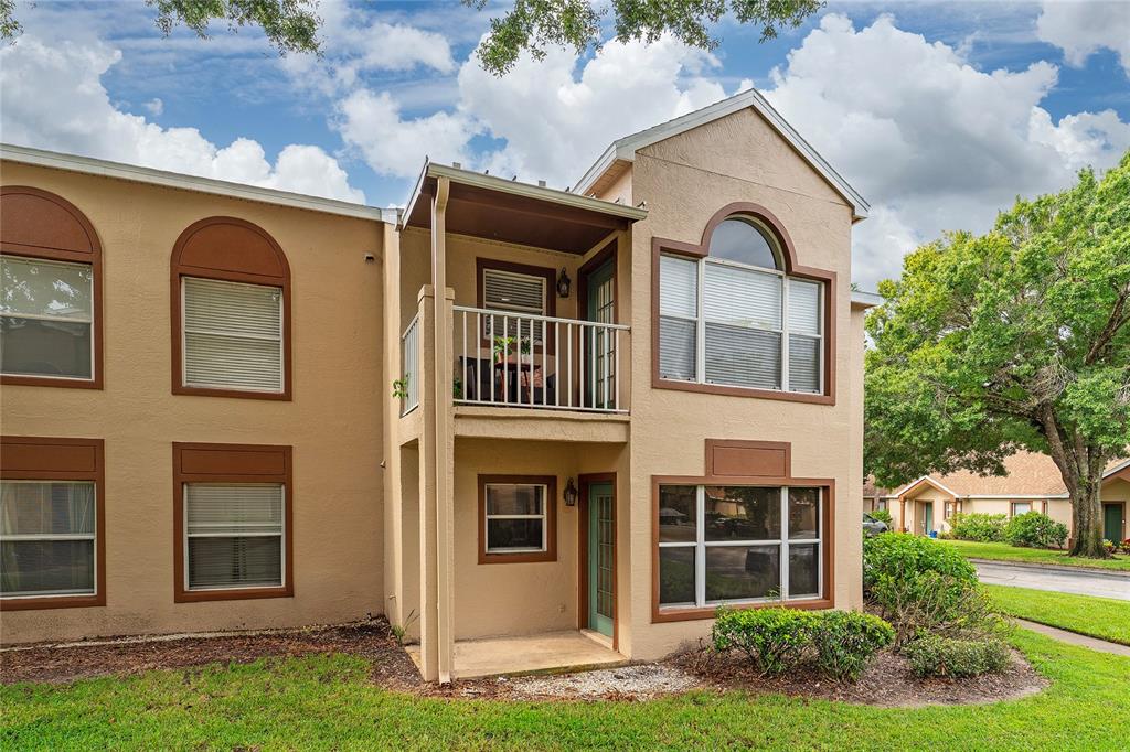A two-story tan stucco apartment building features a second-floor balcony and a ground-level patio — 5424 E MICHIGAN STREET UNIT 7, ORLANDO, FL