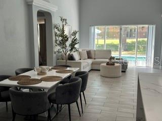 An open-concept dining and living area features tile floors, a white dining set, and sectional — 442 VIZCAY WAY, DAVENPORT, FL