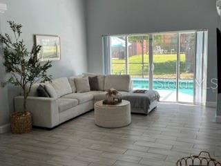 A living room features a light-colored sectional sofa, a round ottoman, and sliding glass doors — 442 VIZCAY WAY, DAVENPORT, FL