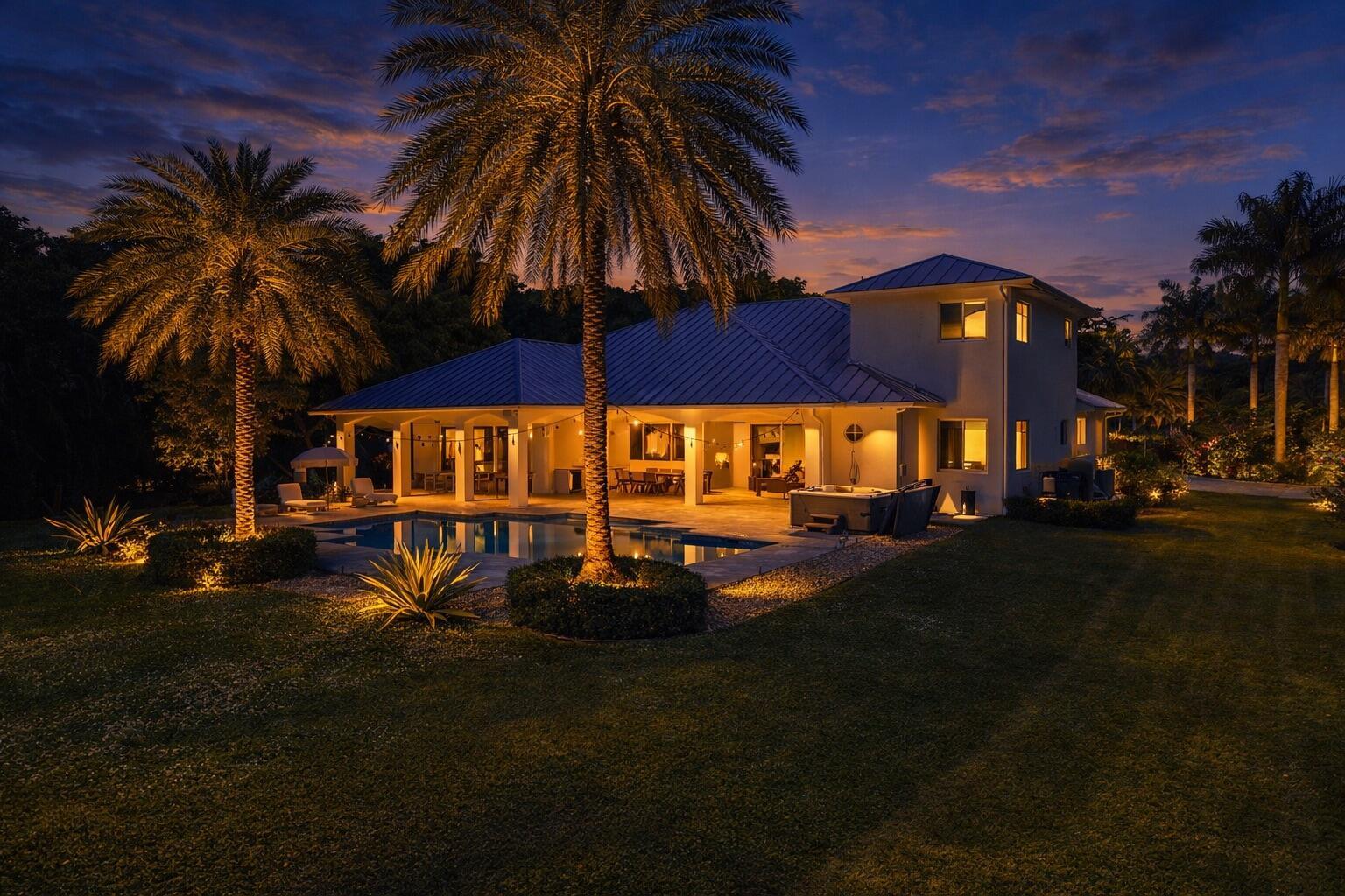 A two-story house with a pool, palm trees, and illuminated patio at twilight — 14600 Sunset Lane, Southwest Ranches FL 33330, SOUTHWEST RANCHES, FL