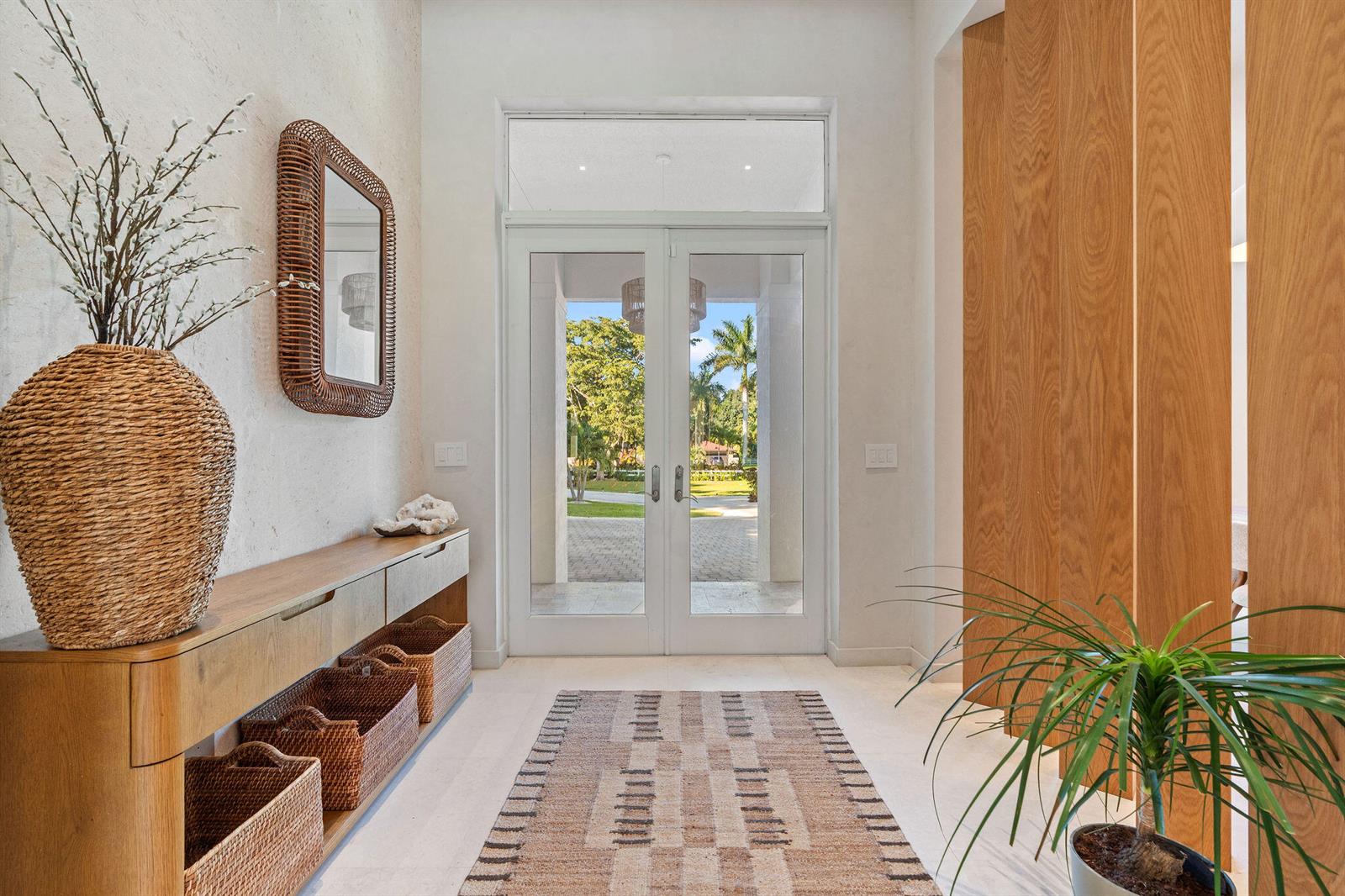 A bright entryway features a wooden console, woven baskets, a patterned rug, and glass doors — 14600 Sunset Lane, Southwest Ranches FL 33330, SOUTHWEST RANCHES, FL