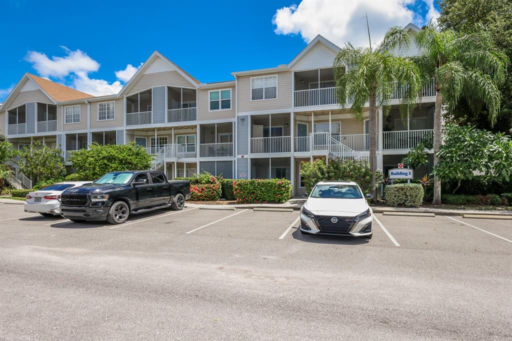 A three-story apartment building with a parking lot and several cars in front — 850 S TAMIAMI TRAIL UNIT 325, SARASOTA, FL