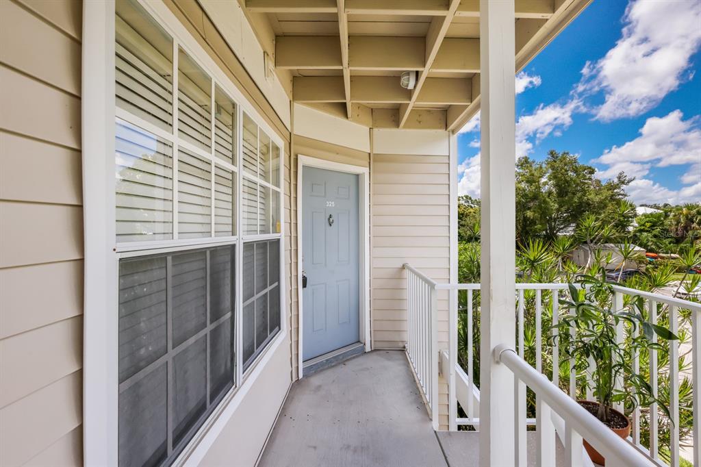 An exterior view of a building balcony featuring a blue door and a large window — 850 S TAMIAMI TRAIL UNIT 325, SARASOTA, FL
