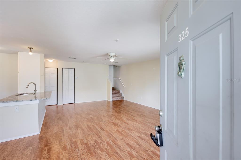 An open-concept living area features wood-look flooring, a kitchen island, and stairs leading upward — 850 S TAMIAMI TRAIL UNIT 325, SARASOTA, FL