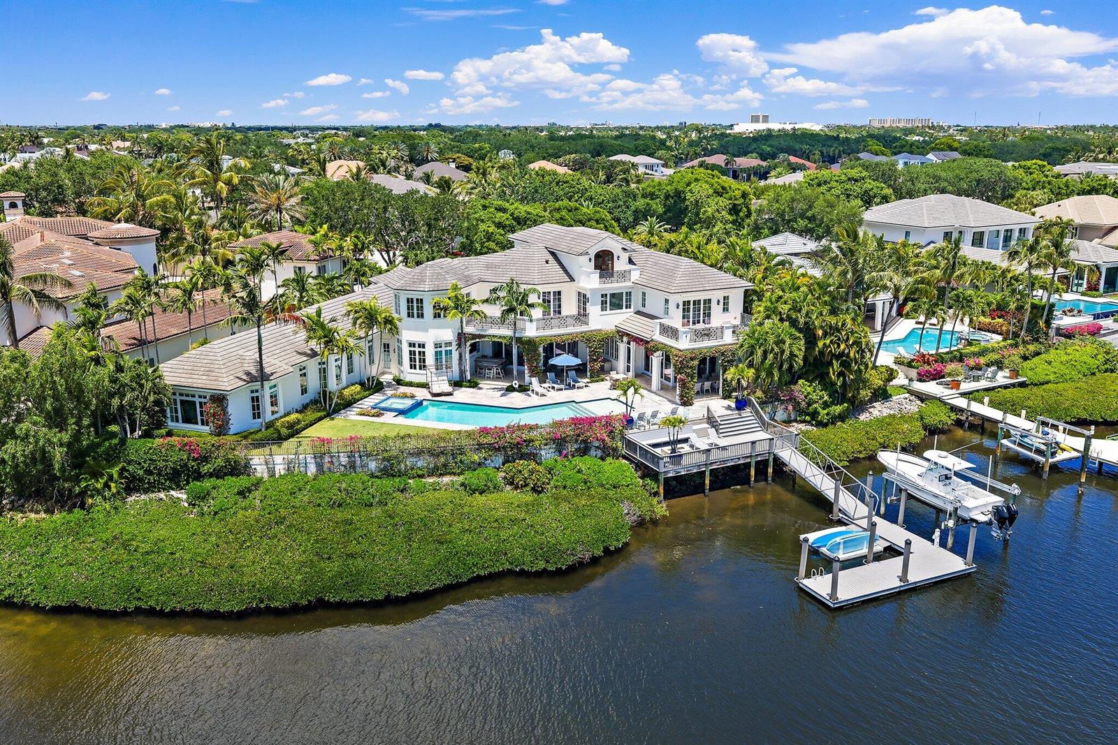An aerial view of a waterfront mansion with a pool, dock, and boat — 103 Quayside Drive, Jupiter FL 33477, JUPITER, FL