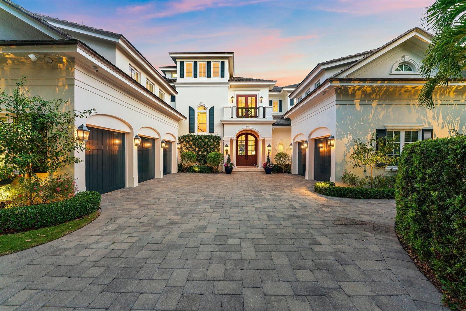 A large Mediterranean-style house with a paved courtyard and multiple garage bays at sunset — 103 Quayside Drive, Jupiter FL 33477, JUPITER, FL