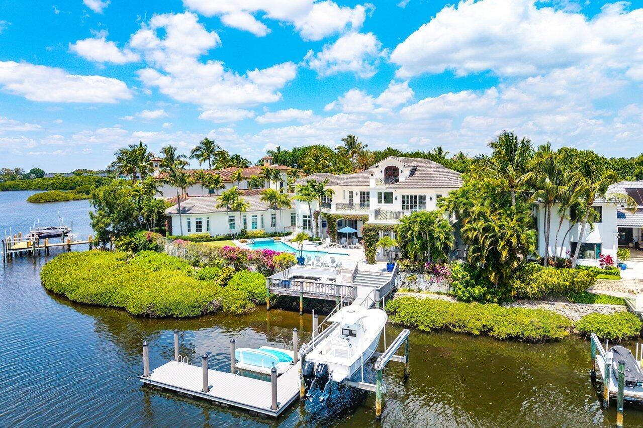 An aerial view of a waterfront mansion with a swimming pool, private dock, and boat — 103 Quayside Drive, Jupiter FL 33477, JUPITER, FL