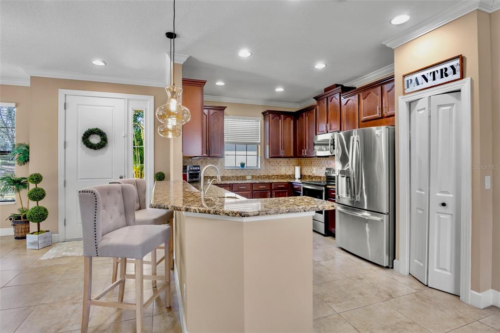 A kitchen features dark wood cabinets, granite countertops, stainless steel appliances, and a breakfast bar — 13218 TORRESINA TERRACE, BRADENTON, FL