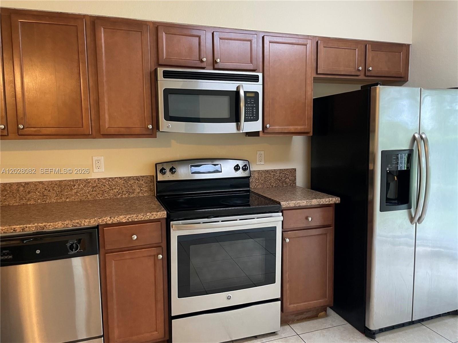 A kitchen features wood cabinets, stainless steel appliances, and speckled laminate countertops — 22541 SW 88th Pl # 6, Cutler Bay FL 33190, CUTLER BAY, FL