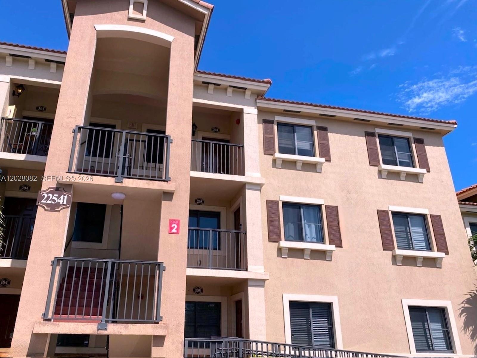 A three-story apartment building exterior features tan stucco walls, brown shutters, and metal railings — 22541 SW 88th Pl # 6, Cutler Bay FL 33190, CUTLER BAY, FL